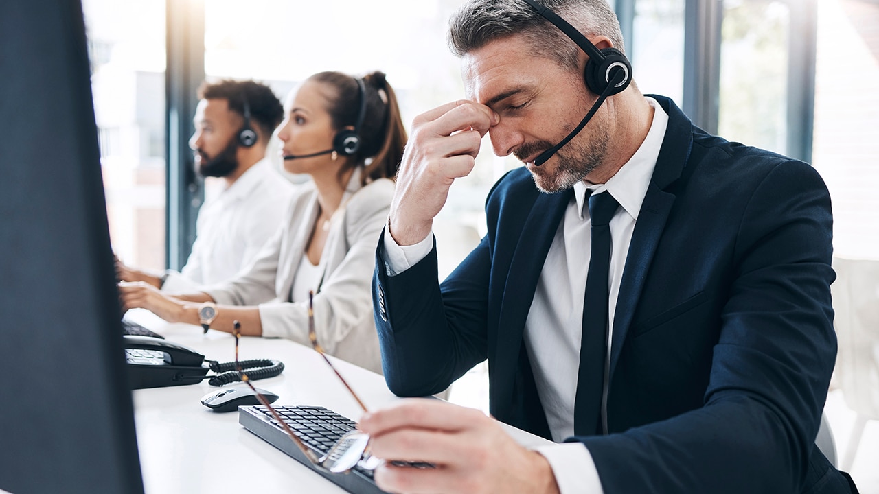 Call center, customer service and man with headache, stress and tired of working in office. Burnout, crm and frustrated male telemarketing consultant in customer support on call with difficult client